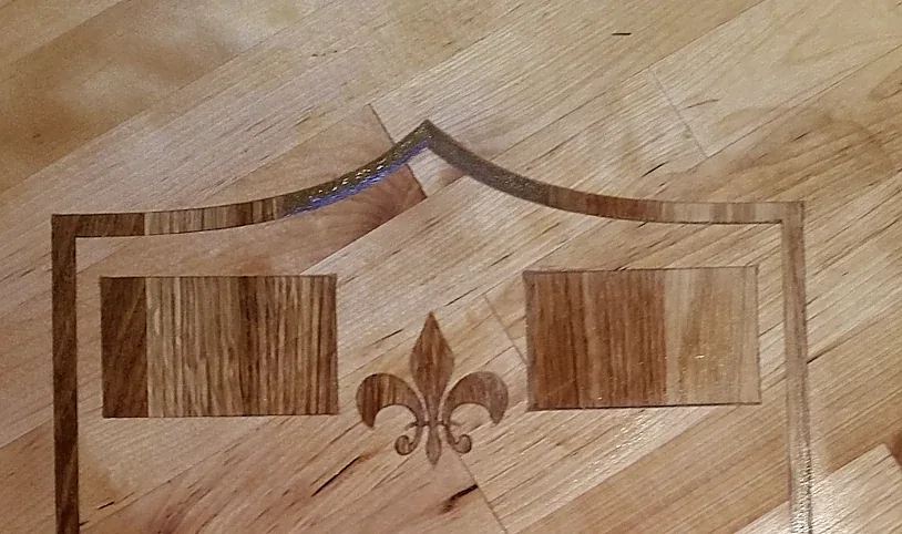 Detail einer Inlay-Arbeit mit eingelegter Lilie zwischen zwei Eichenfeldern
